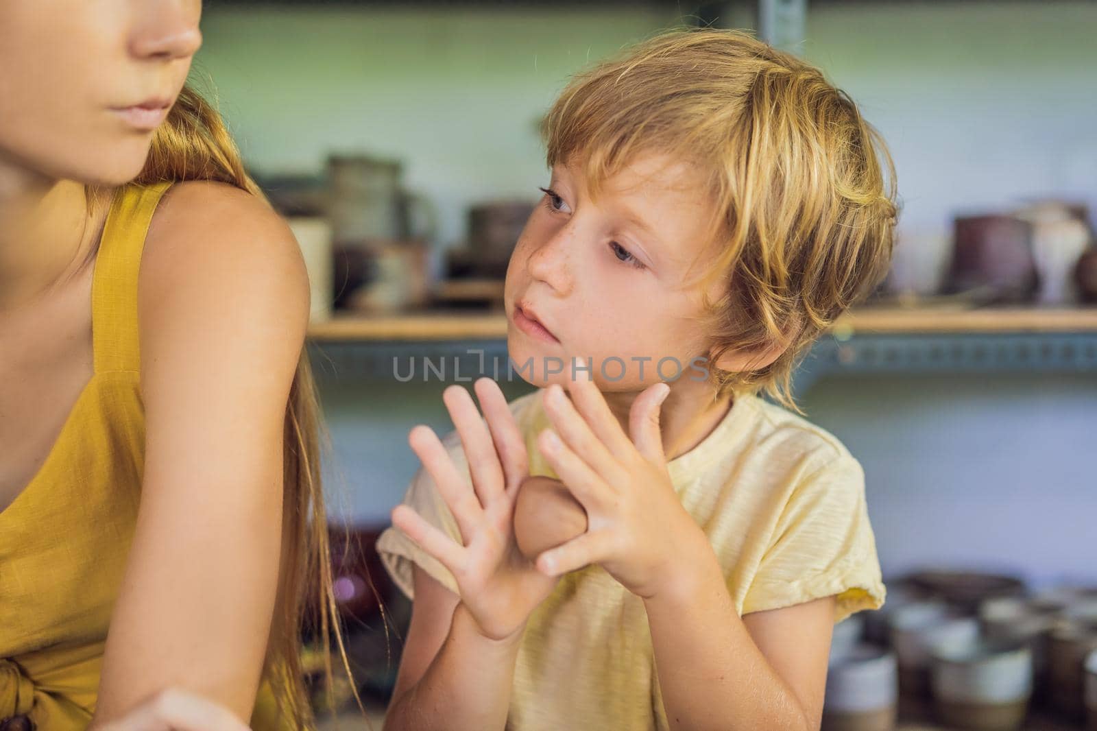 mother and son doing ceramic pot in pottery workshop by galitskaya