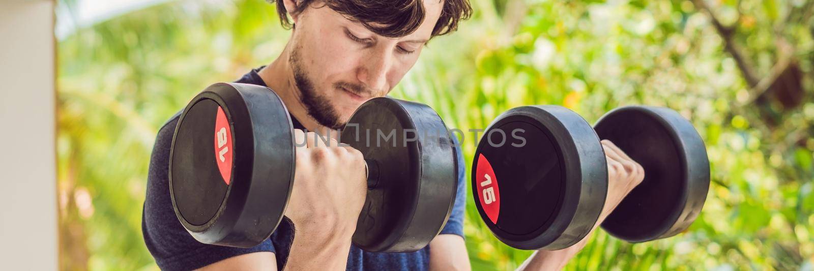 Bicep curl - weight training fitness man outside working out arms lifting dumbbells doing biceps curls. Male sports model exercising outdoors as part of healthy lifestyle. BANNER, long format