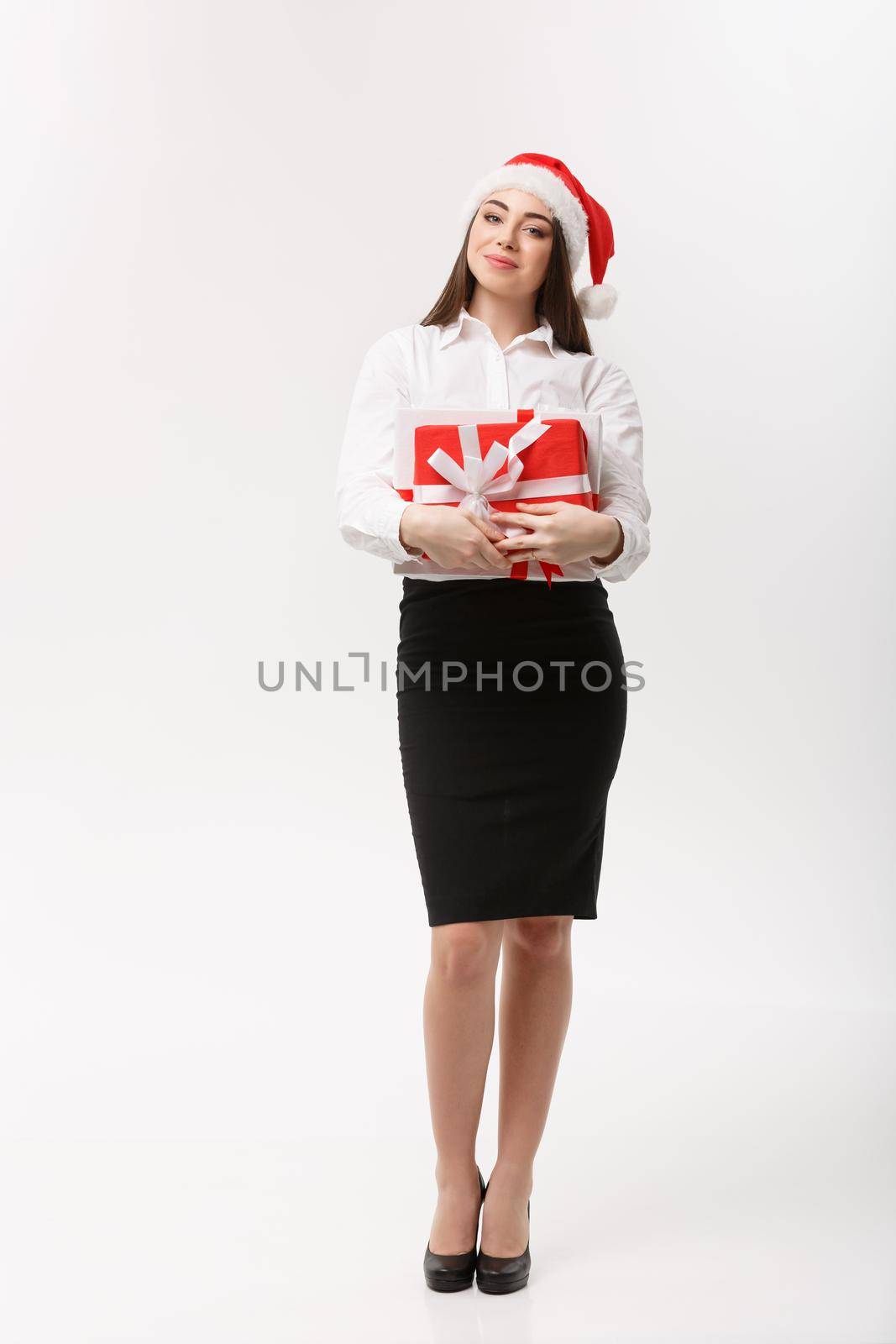 Business Concept - Beautiful young caucasian business woman with santa hat holding gift box with copy space on side. by Benzoix