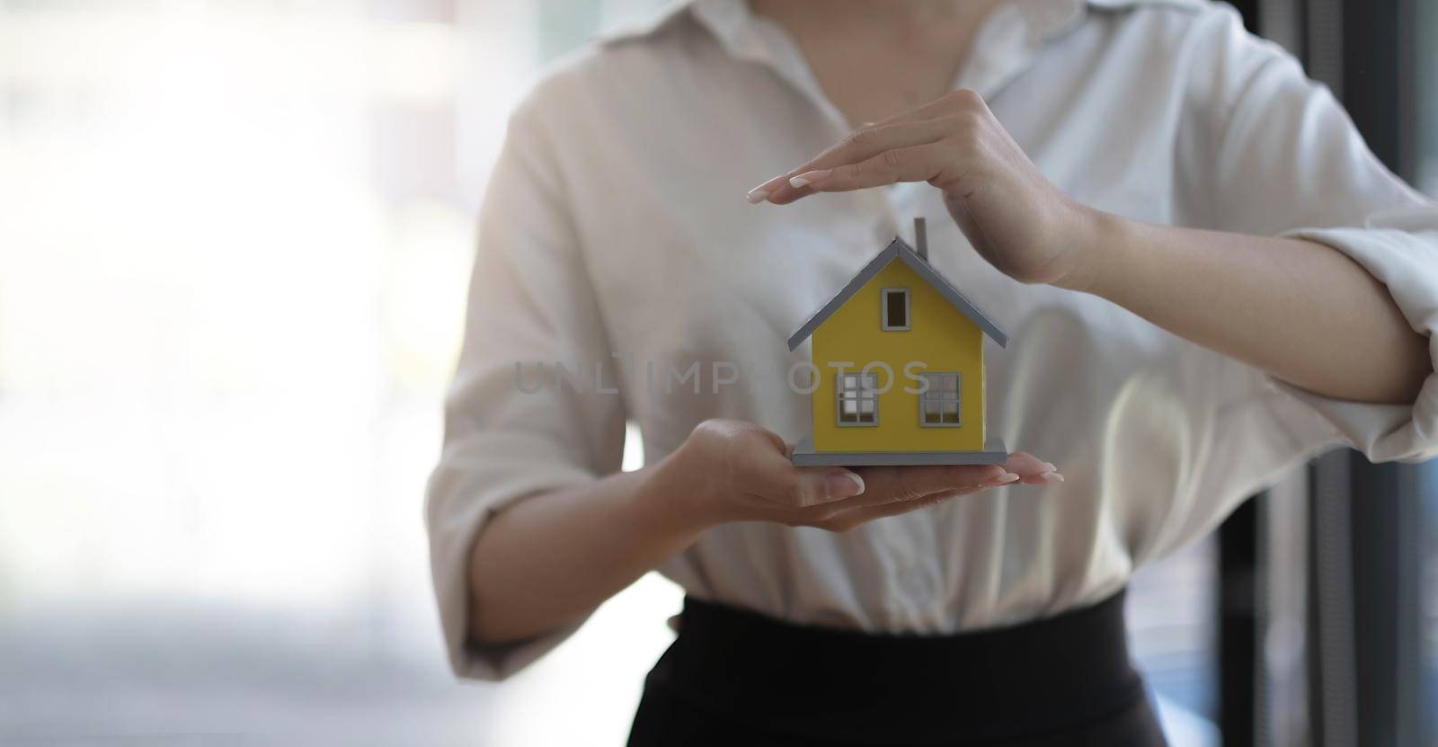 real estate agent use their hands to protect the red roofs, the concept of protecting houses using the gestures and symbols of real estate investors, taking care of credit and contracts..
