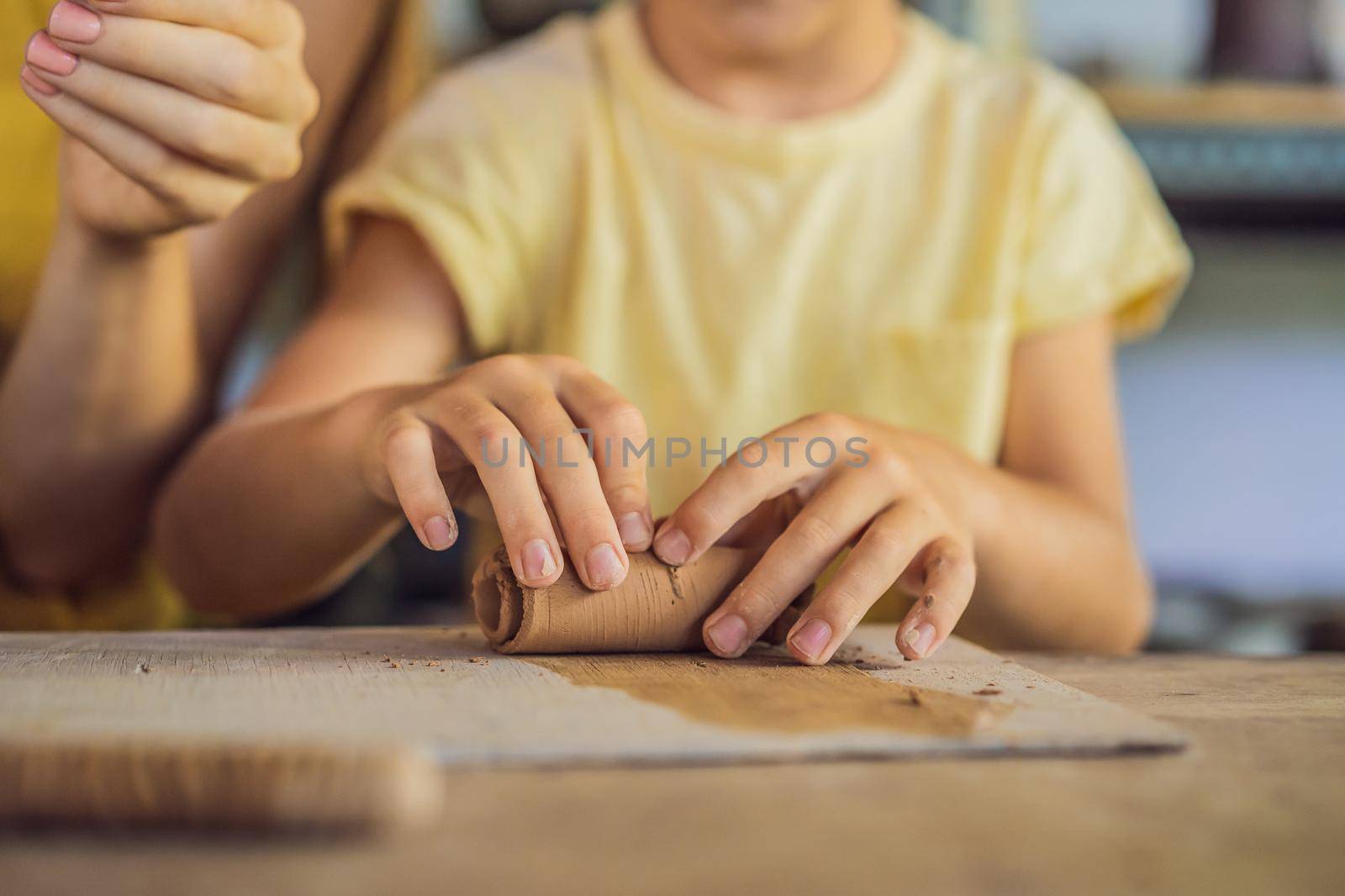 mother and son doing ceramic pot in pottery workshop by galitskaya