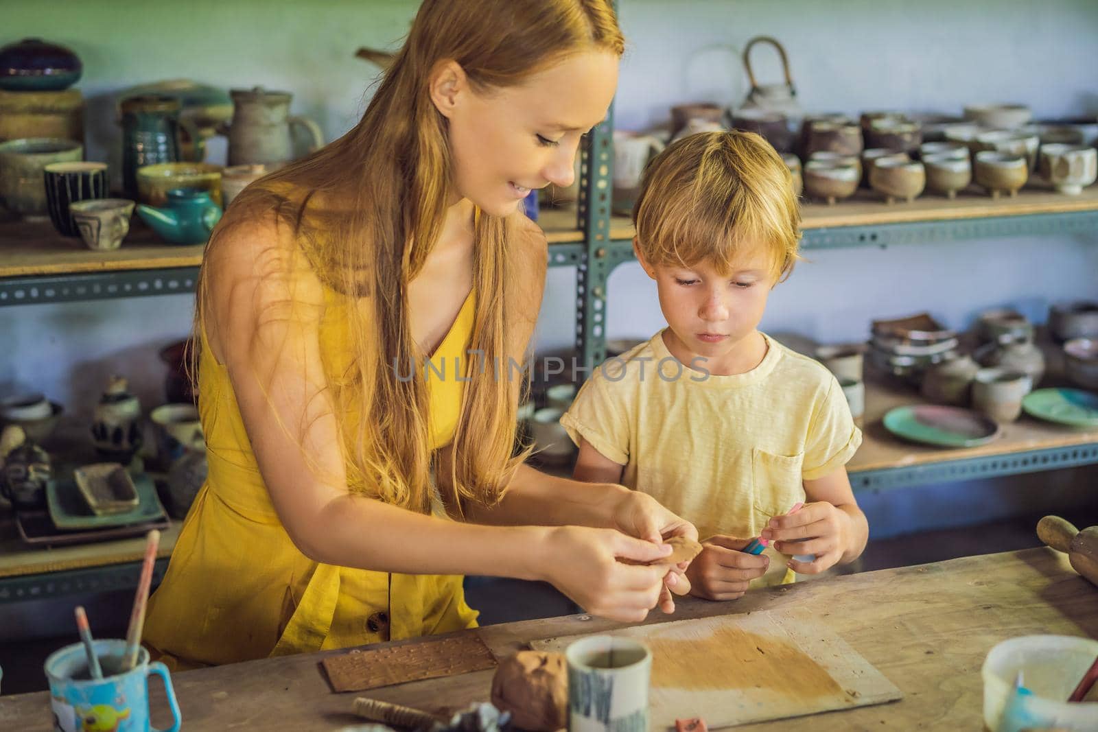 mother and son doing ceramic pot in pottery workshop by galitskaya