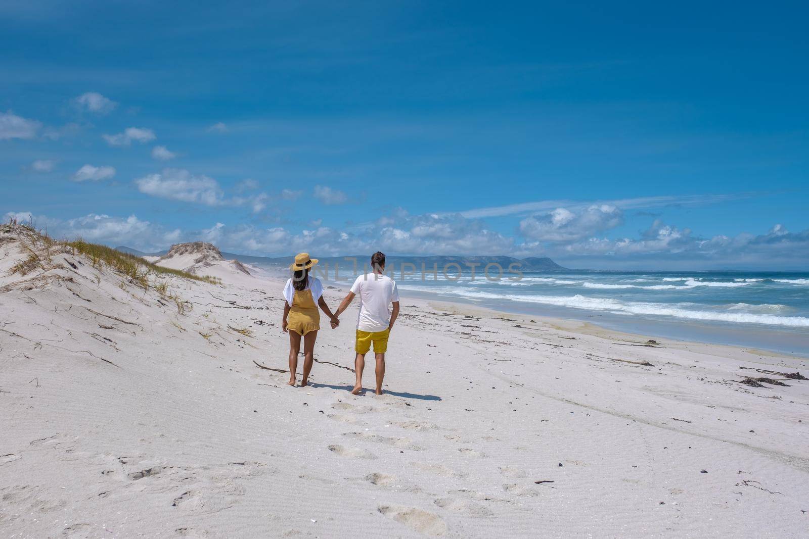 Cape Nature Walker Bay beach near Hermanus Western Cape South Africa. white beach and blue sky with clouds, sand dunes at the beach in South Africa, couple man and woman at the beach