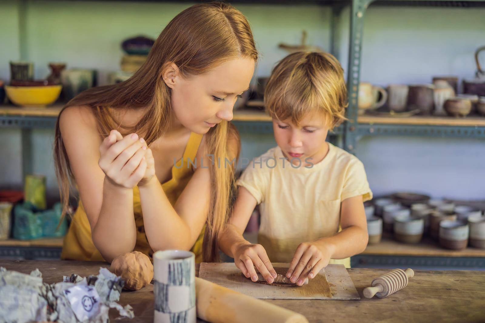 mother and son doing ceramic pot in pottery workshop.