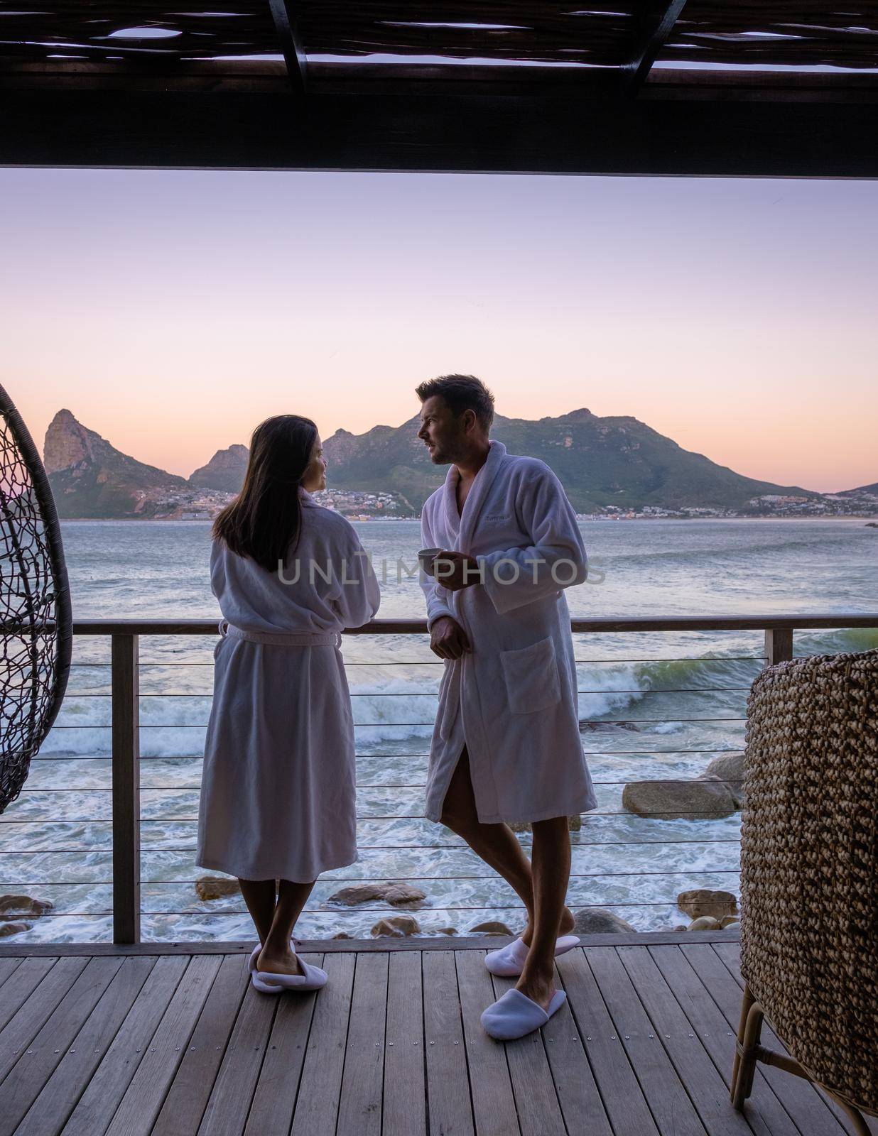 couple man and woman drinking coffee during on balcony sunrise at vacation in Cape Town South Africa by fokkebok