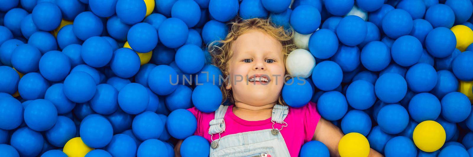 BANNER, LONG FORMAT Child playing in ball pit. Colorful toys for kids. Kindergarten or preschool play room. Toddler kid at day care indoor playground. Balls pool for children. Birthday party for active preschooler by galitskaya
