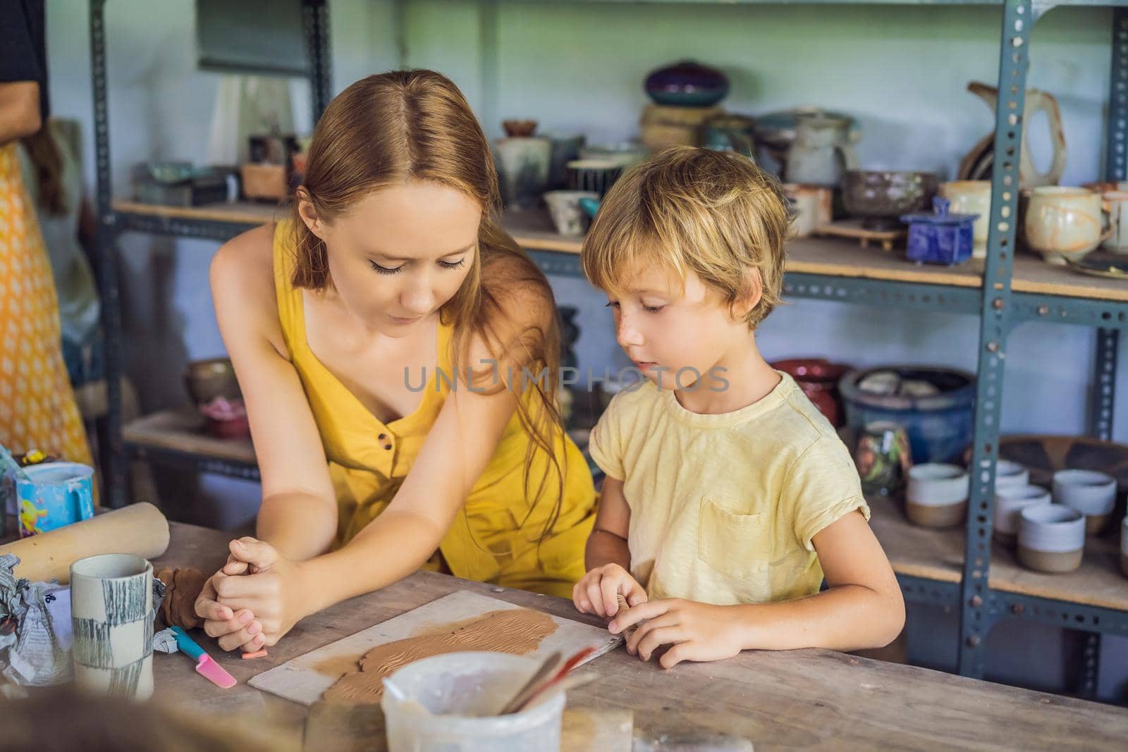 mother and son doing ceramic pot in pottery workshop.