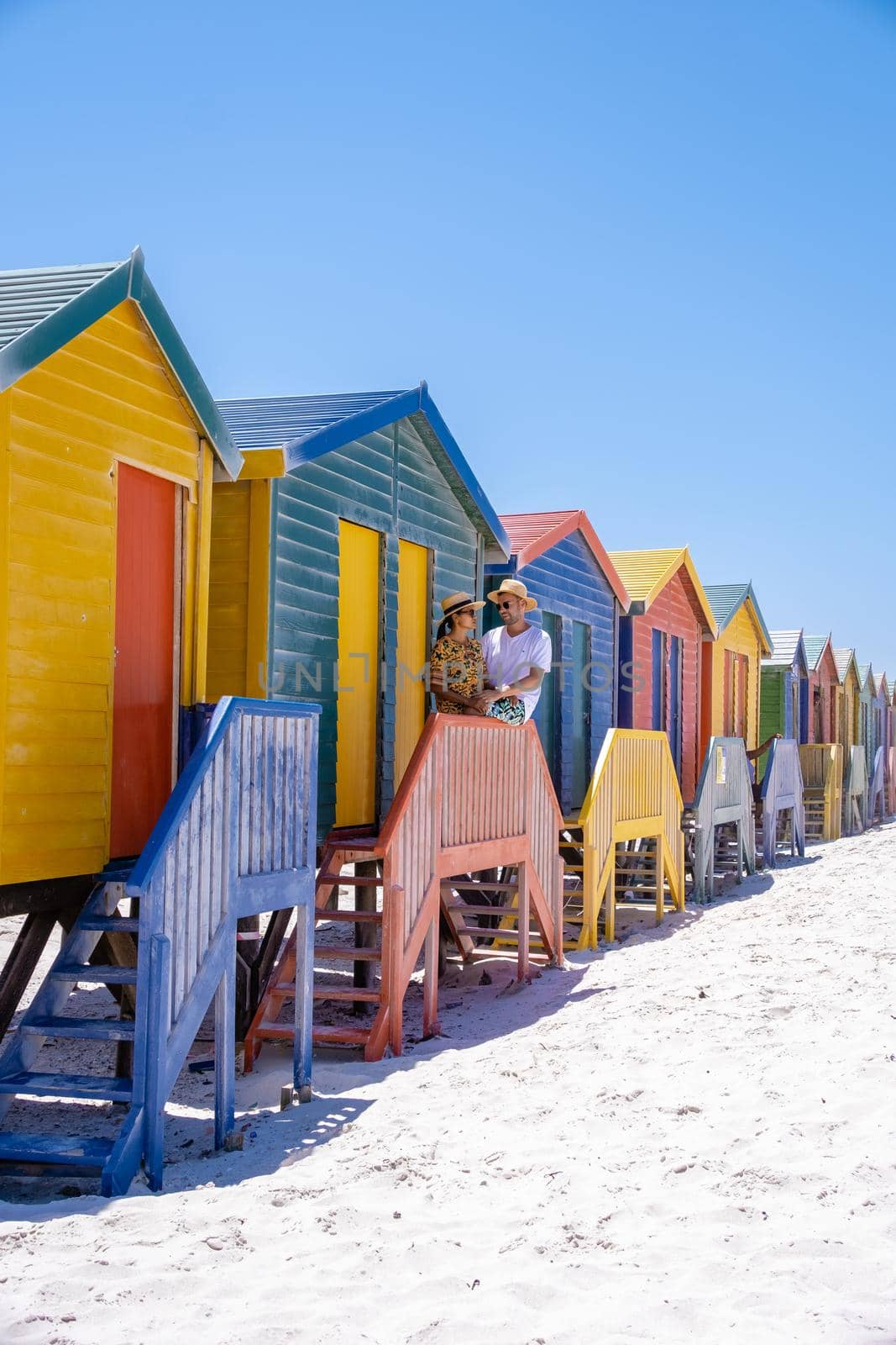 couple man and woman visiting the beach at Muizenberg, colorful beach house at Muizenberg beach Cape Town,beach huts, Muizenberg, Cape Town, False Bay, South Africa by fokkebok
