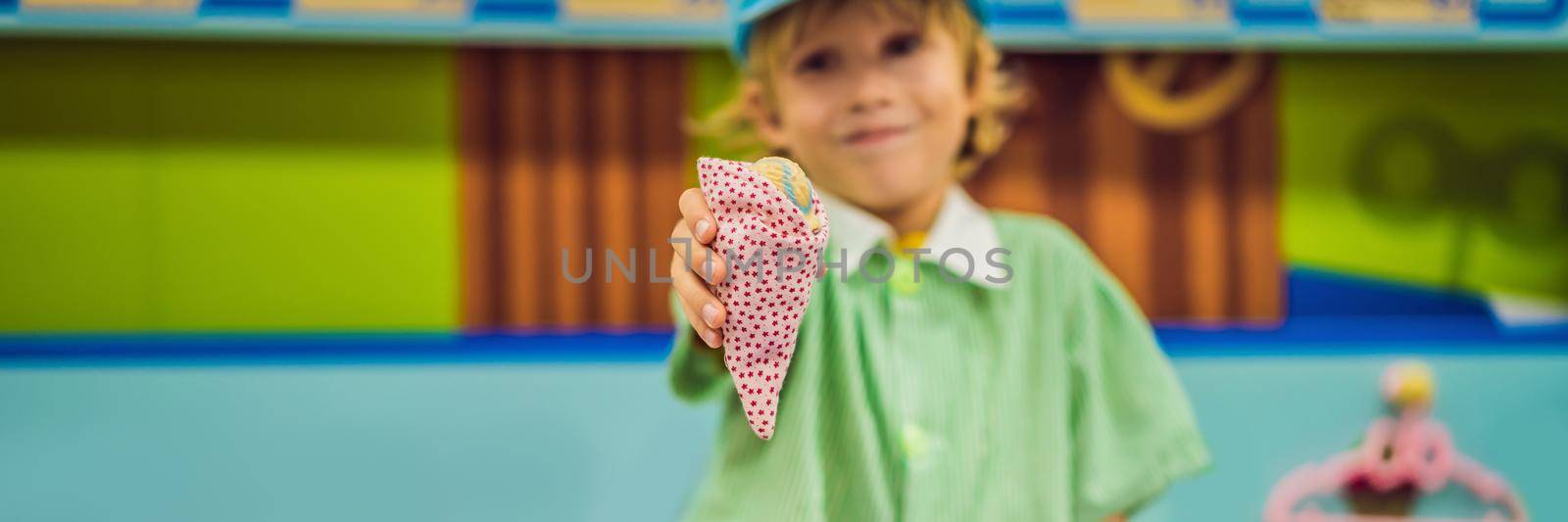 A boy plays in a toy kitchen, makes a toy ice cream BANNER, LONG FORMAT by galitskaya