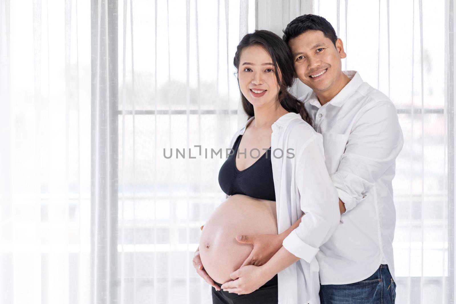 happy pregnant woman with husband with window background