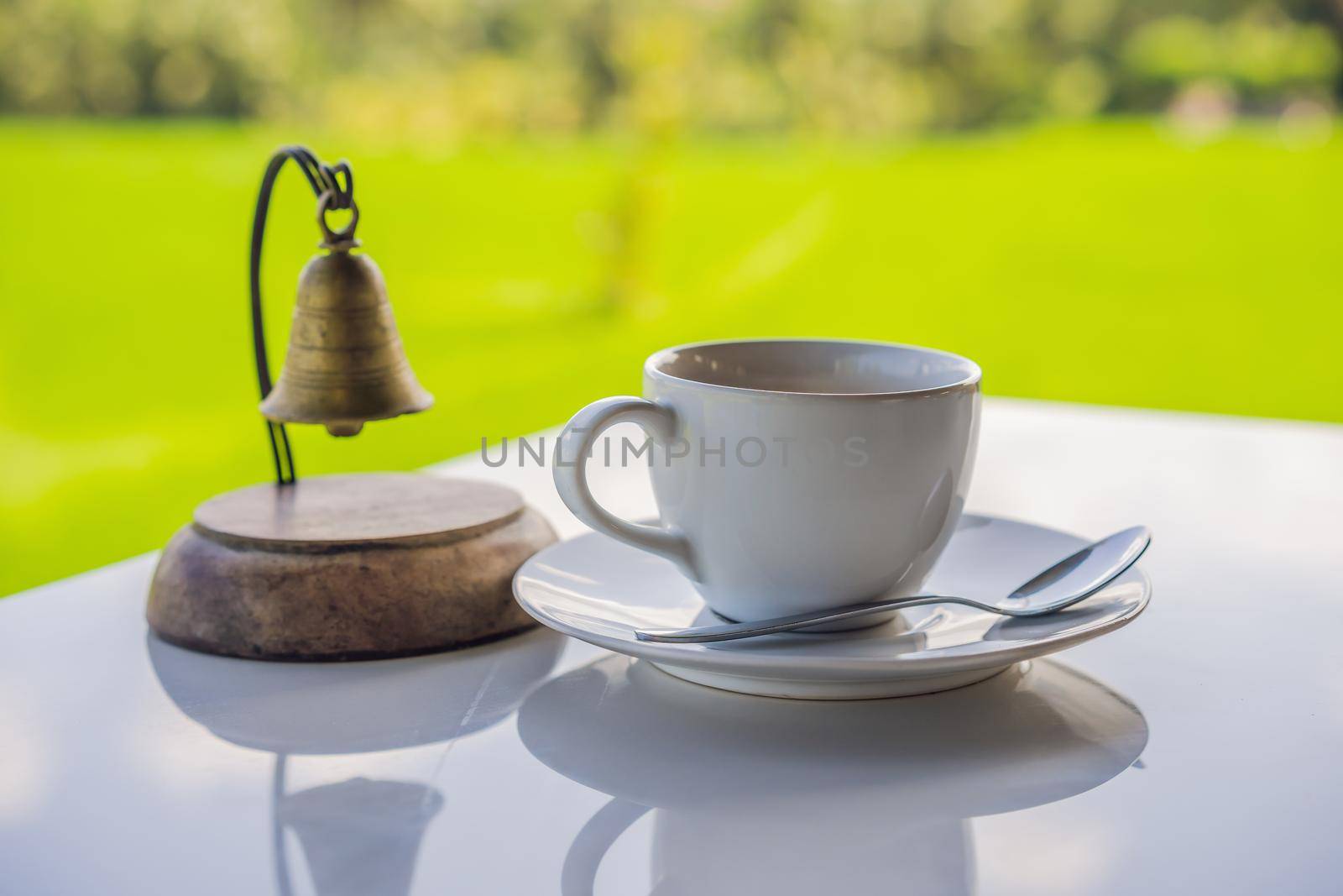 Cup of hot tea with sacking on the wooden table and the rice fields background.