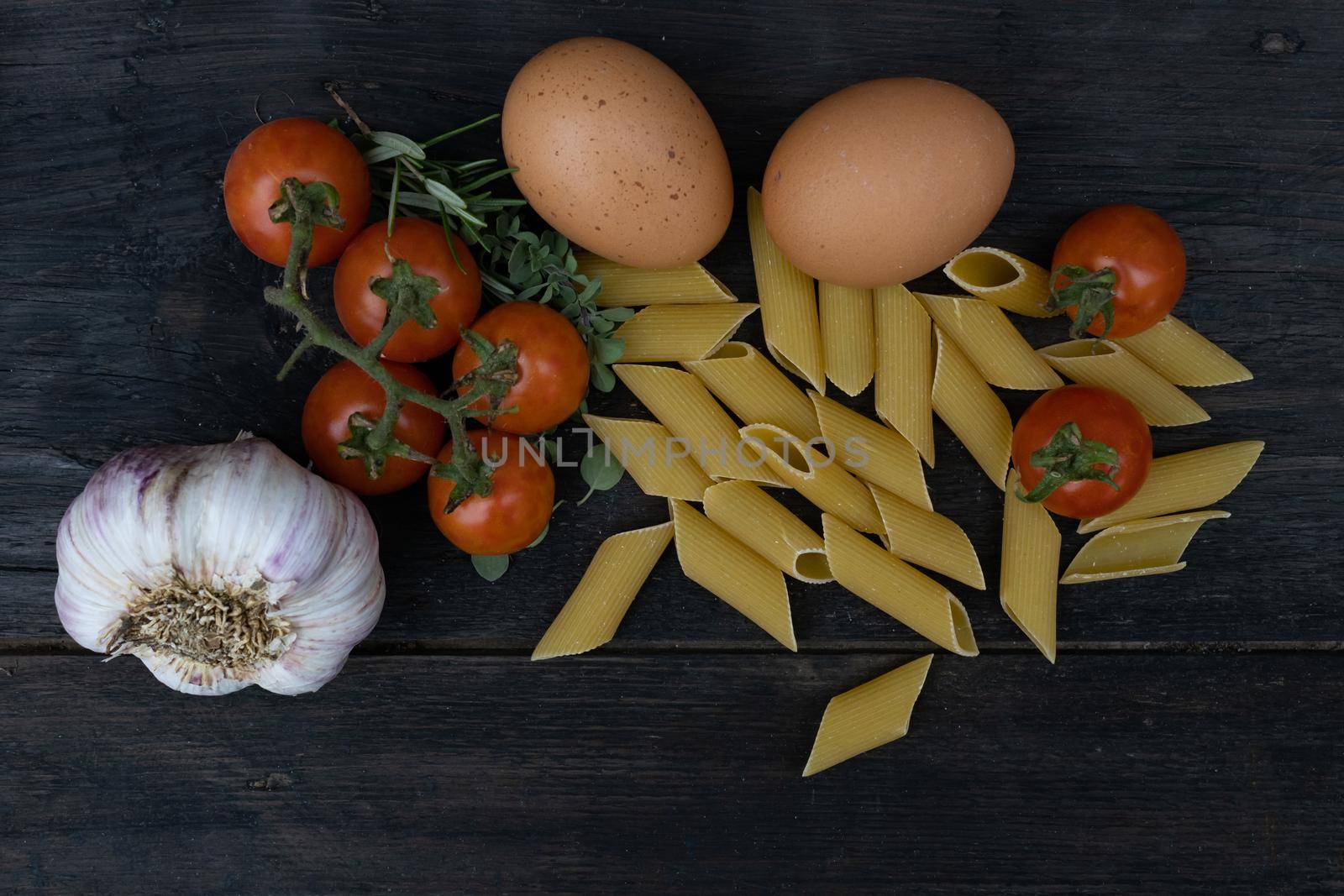 kitchen background with noodles, eggs, cherry tomatoes, and garlic on rusti wood