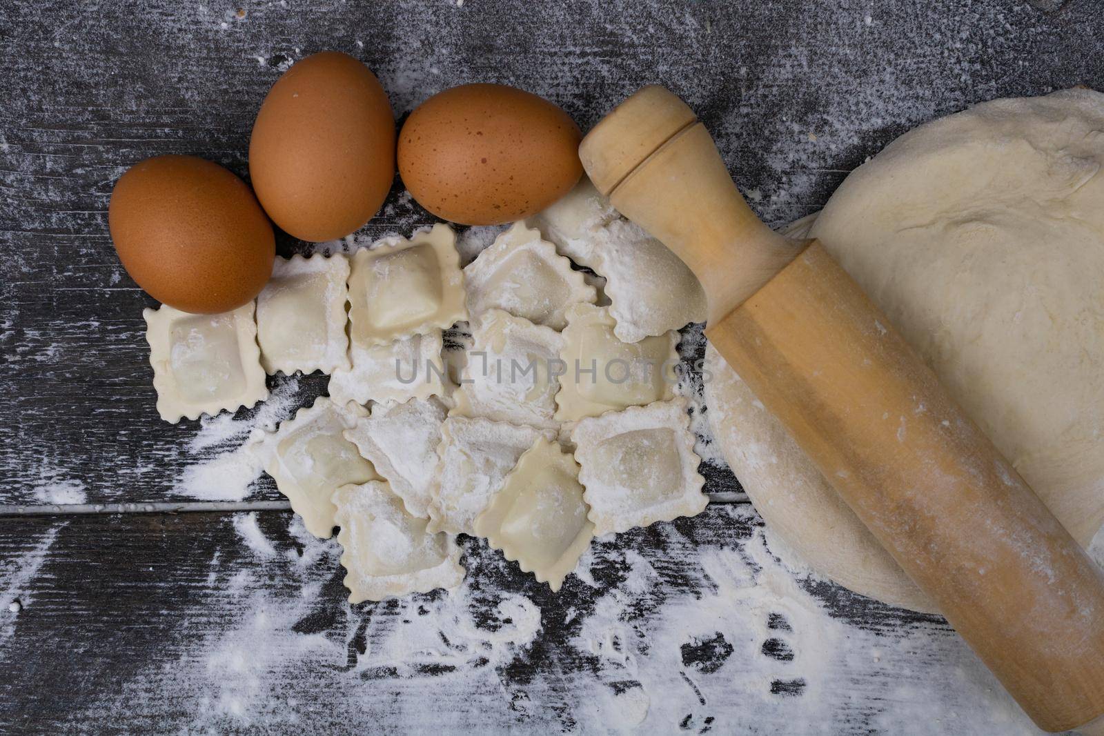top view rolling pin with dough, eggs, flour and ravioli