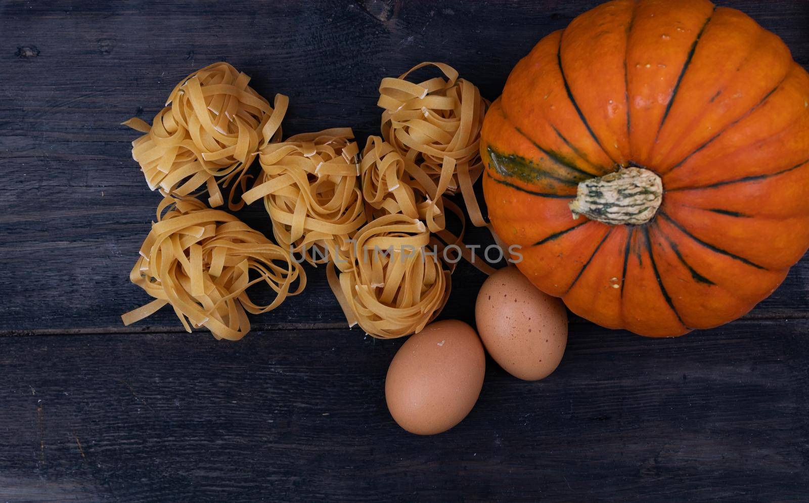Cooking background with pumpkin noodles on wood
