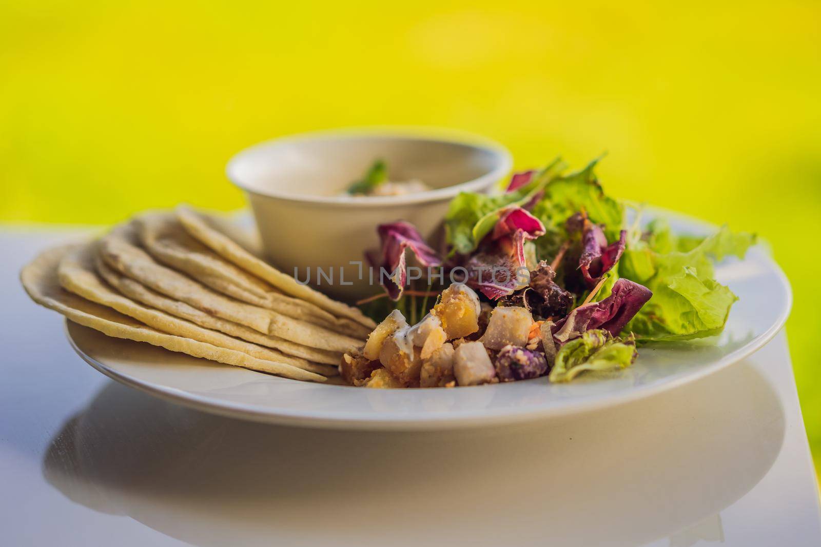 Hummus with tortillas on a white table.