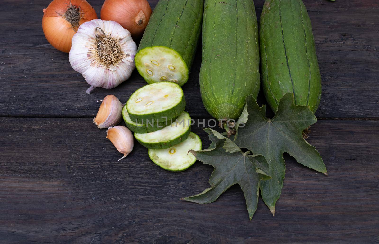 cuisine with luffa garlic and onion on rustic wooden background