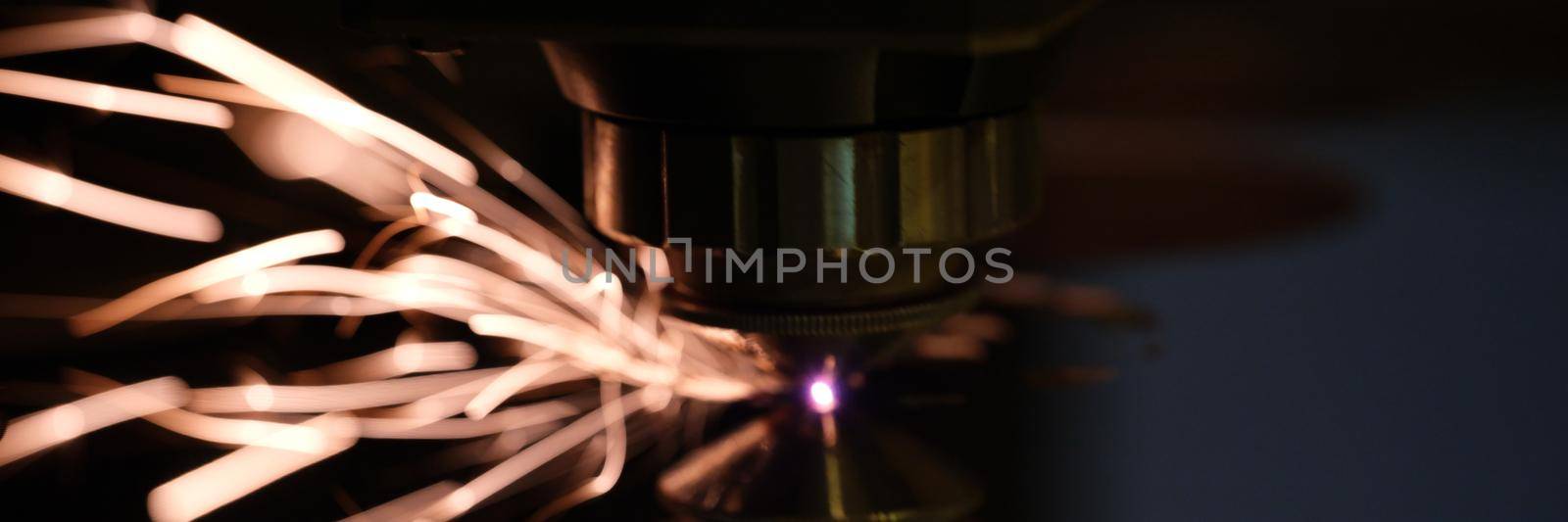Laser machine cutting metal sheet with sparks blurred background. Metalworking concept