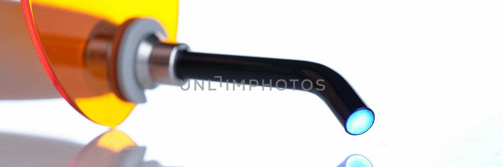 Dental apparatus curing light on white background with reflection closeup by kuprevich