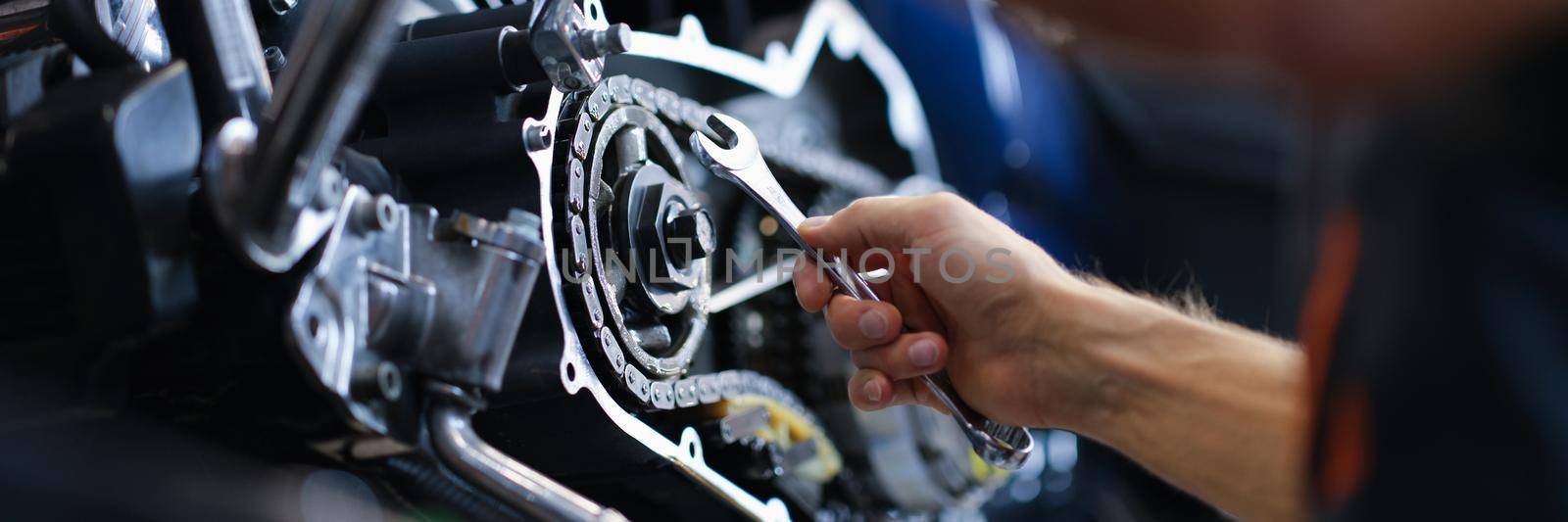 Master repairman repairing motorcycle with wrench closeup. Repair and maintenance of motorcycle equipment concept