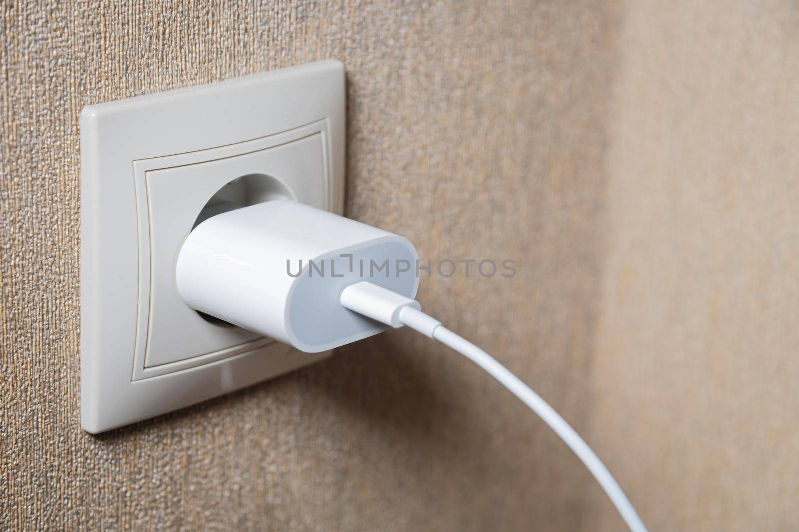 charger in the socket on the wall, close-up.