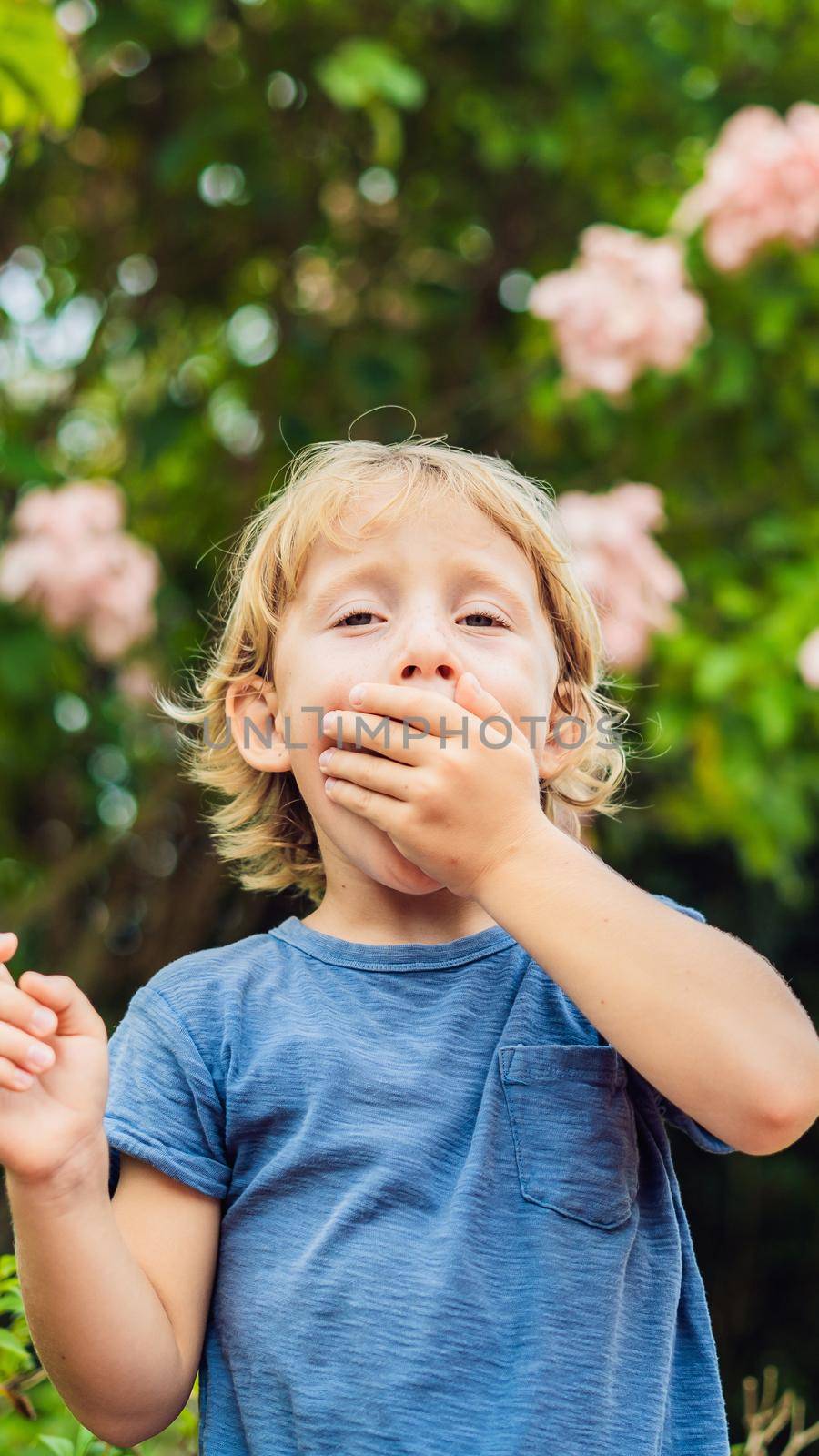 Boy blowing nose in front of blooming tree. Spring allergy concept. Children's allergies VERTICAL FORMAT for Instagram mobile story or stories size. Mobile wallpaper by galitskaya
