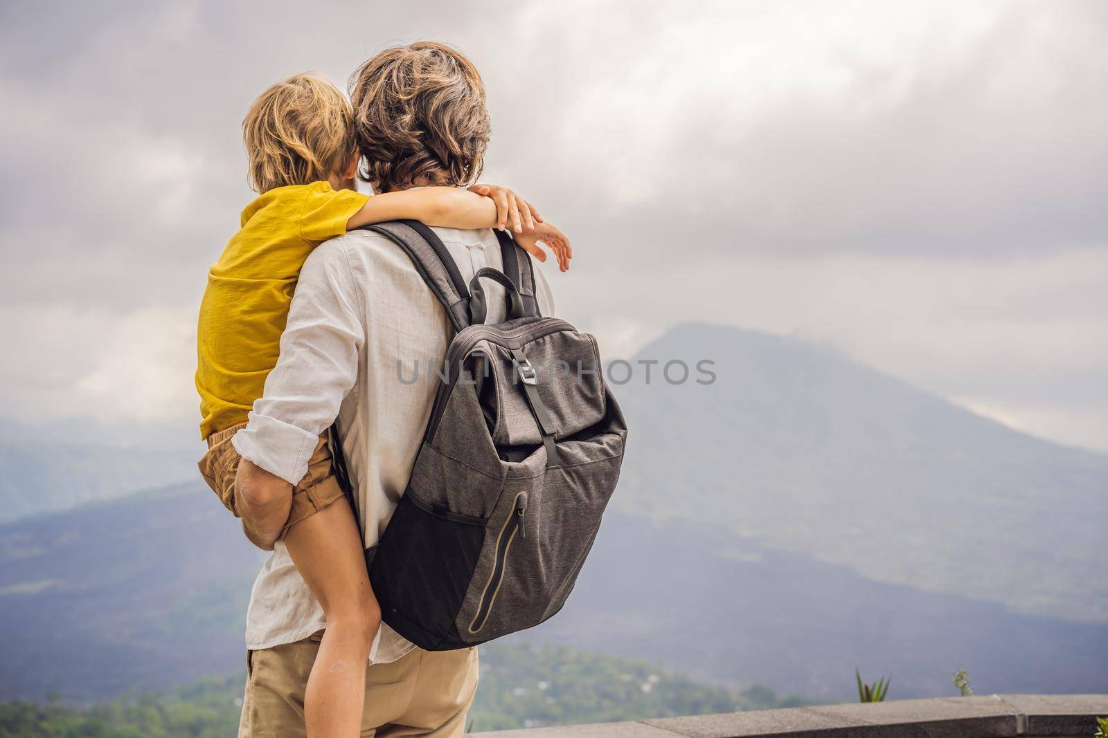 Dad and son tourists on background looking at Batur volcano. Indonesia. Traveling with kids concept by galitskaya