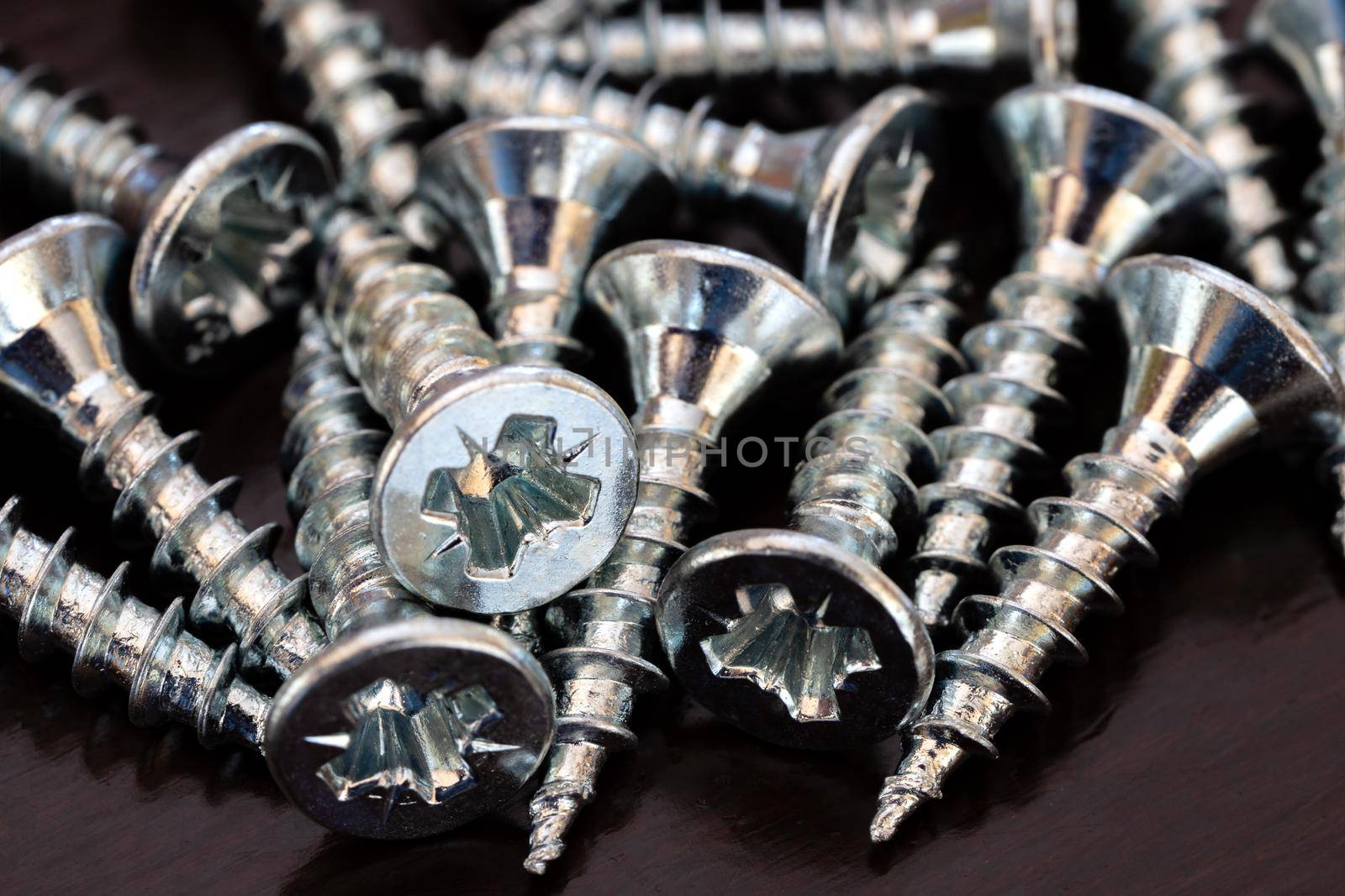 A pile of screws on the black table. Close up