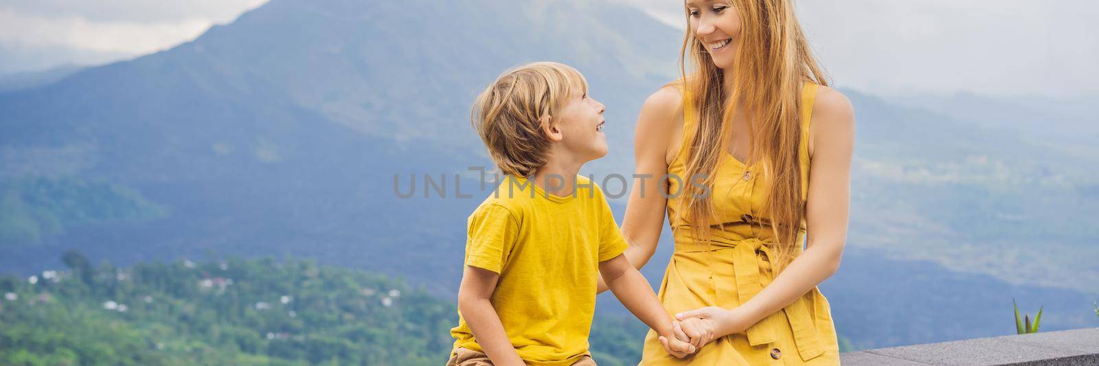 Mom and son tourists on background looking at Batur volcano. Indonesia. Traveling with kids concept. BANNER, LONG FORMAT