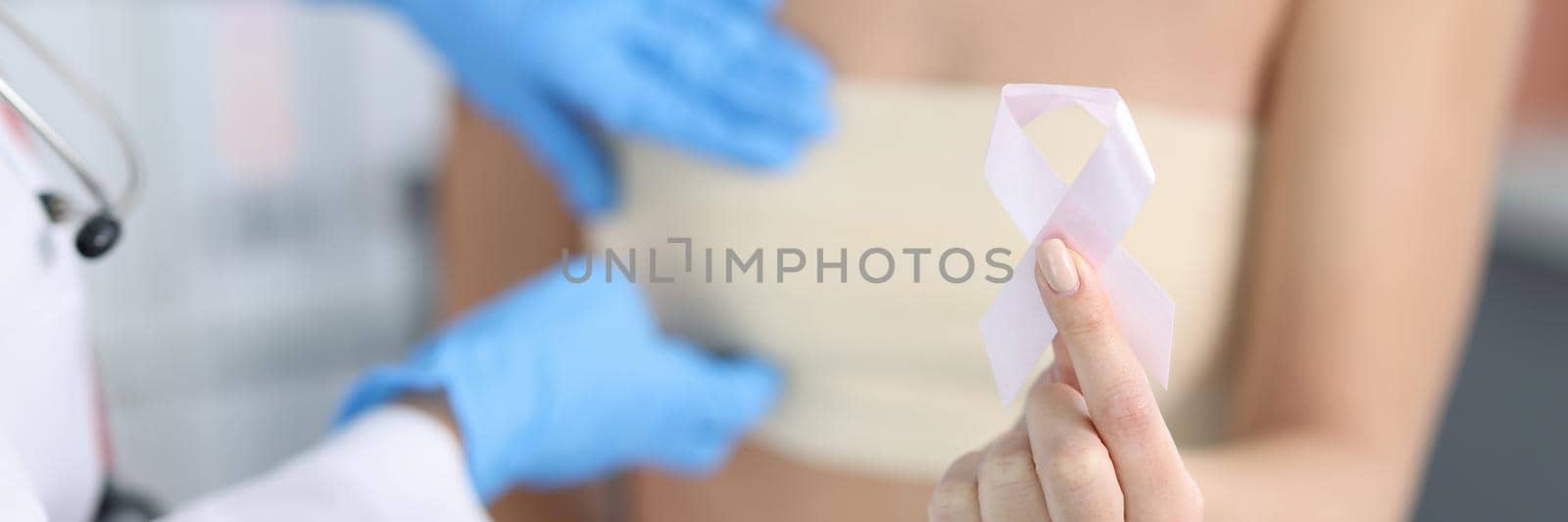 Doctor gynecologist examining patient breast with pink tape closeup. Breast cancer day concept