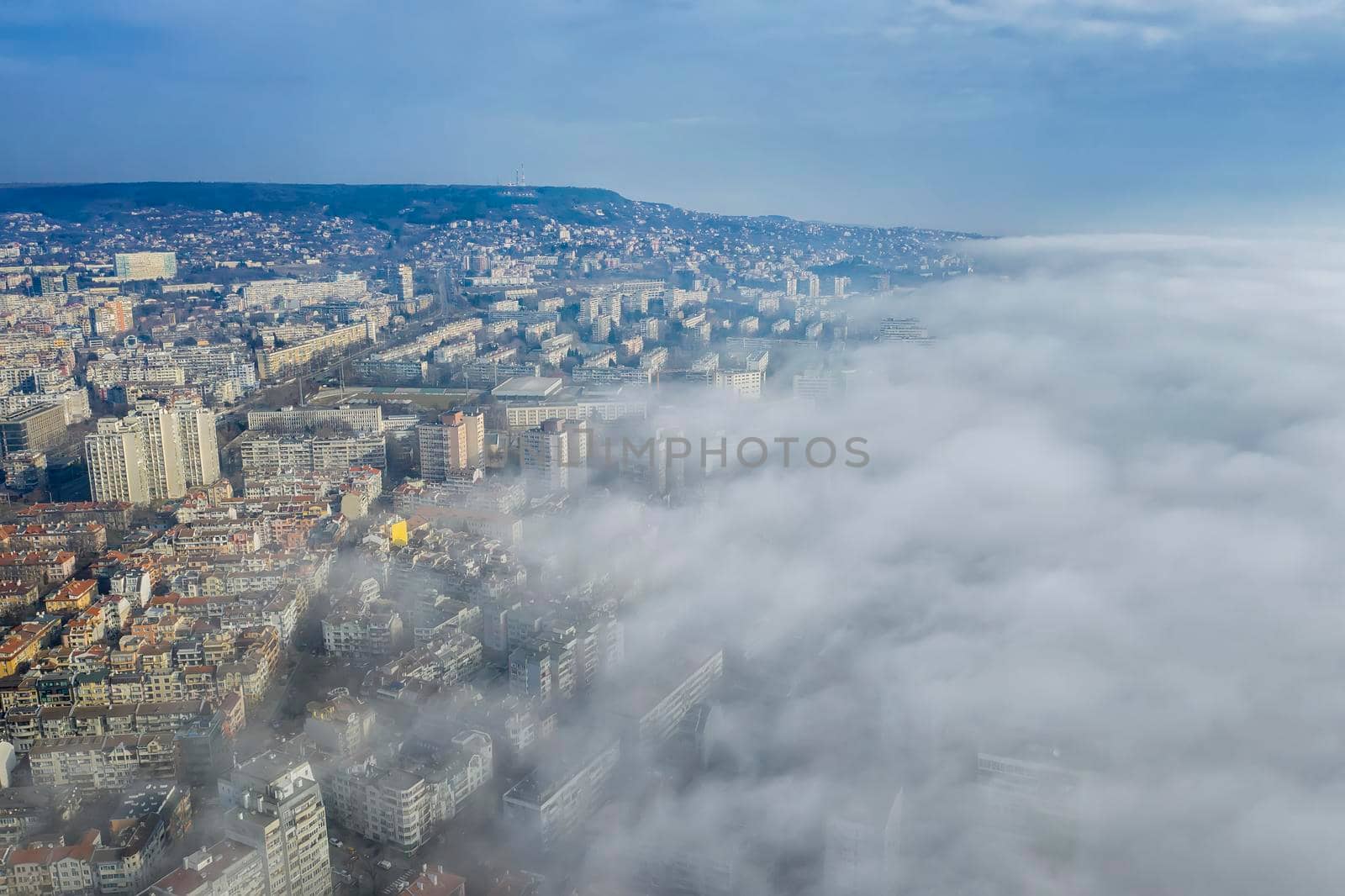 Fog clouds coming over the city from sea, aerial landscape from a drone. View from above. 