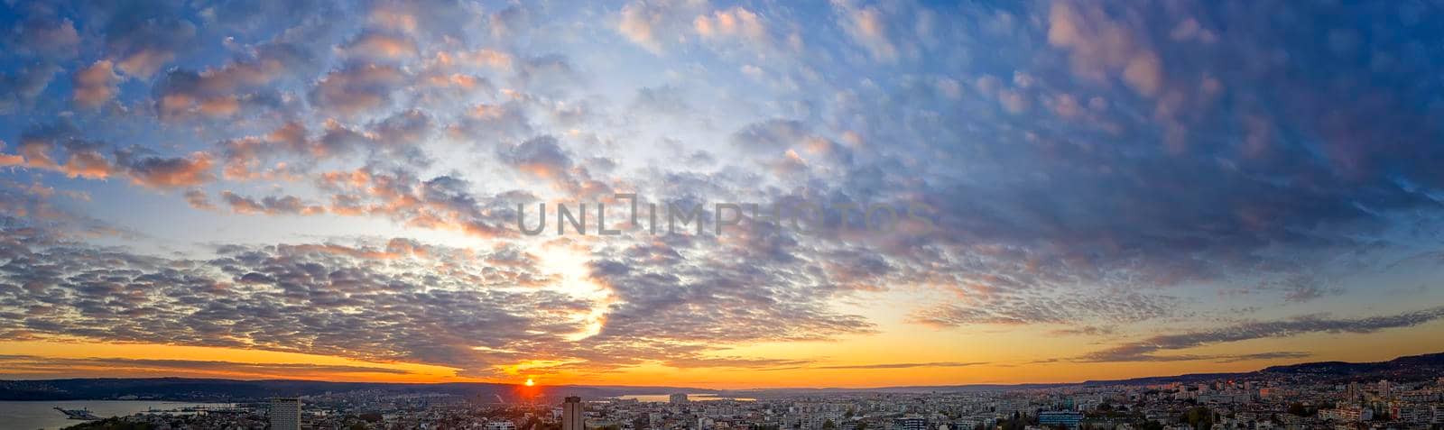 Amazing scenic view of the colorful sky with the sun over the city. Panoramic view from a drone.
