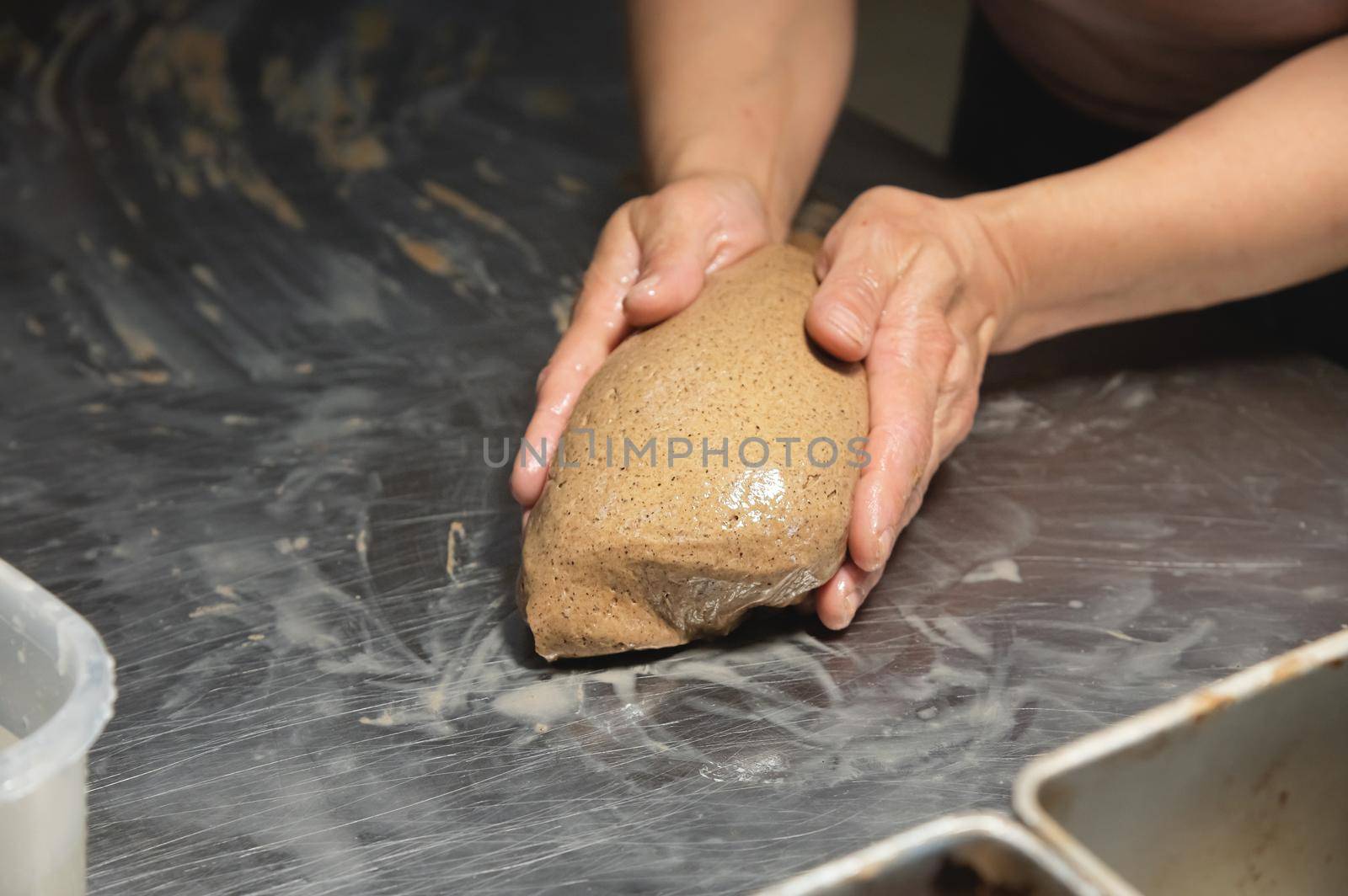 Women's hands carry out actions with raw bread. Dough before dipping into a bakery oven.