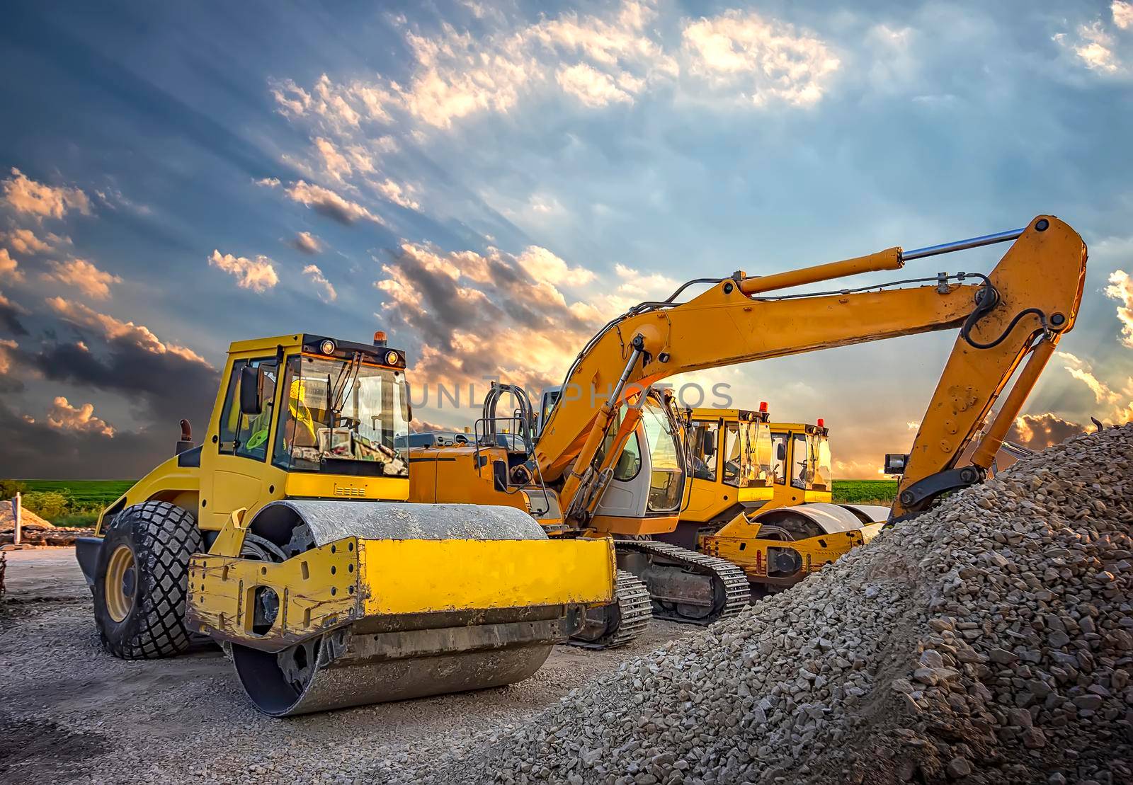 Parked drum roller and excavators at the construction site, after work