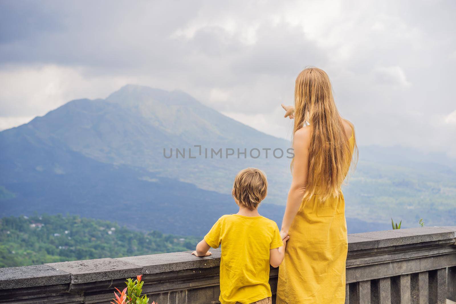 Mom and son tourists on background looking at Batur volcano. Indonesia. Traveling with kids concept by galitskaya