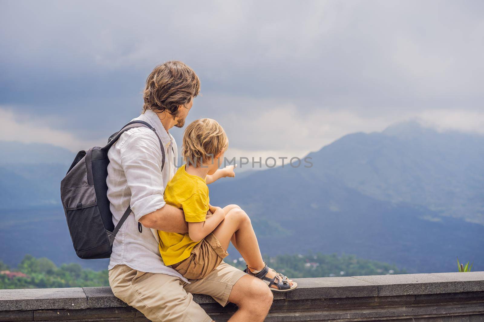 Dad and son tourists on background looking at Batur volcano. Indonesia. Traveling with kids concept.