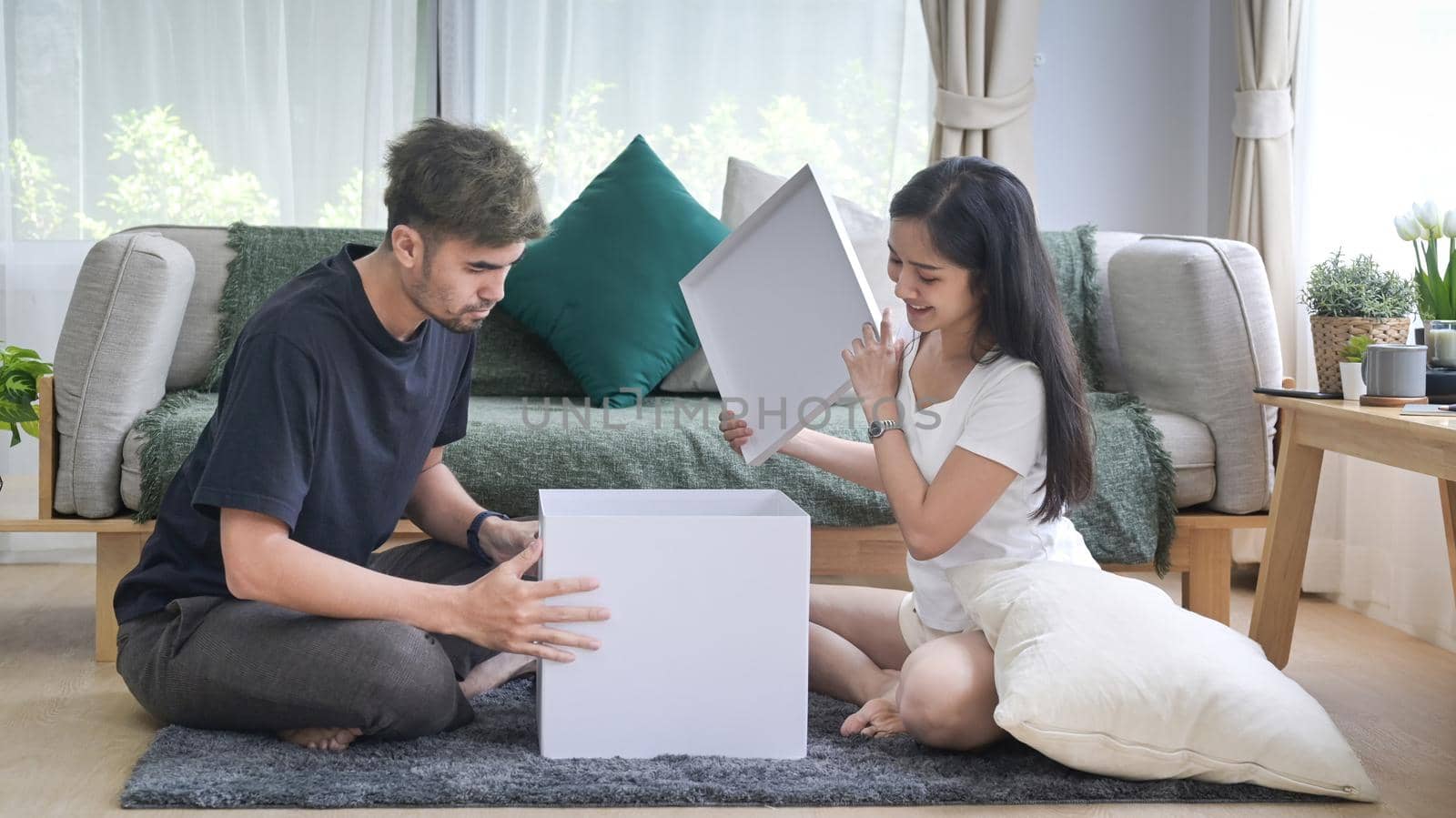 Young couple unpacking cardboard boxes in living room. Relocation house renovation, removals concept by prathanchorruangsak