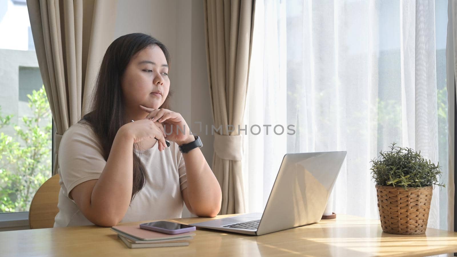 Thoughtful female freelancer working online with laptop computer at home.