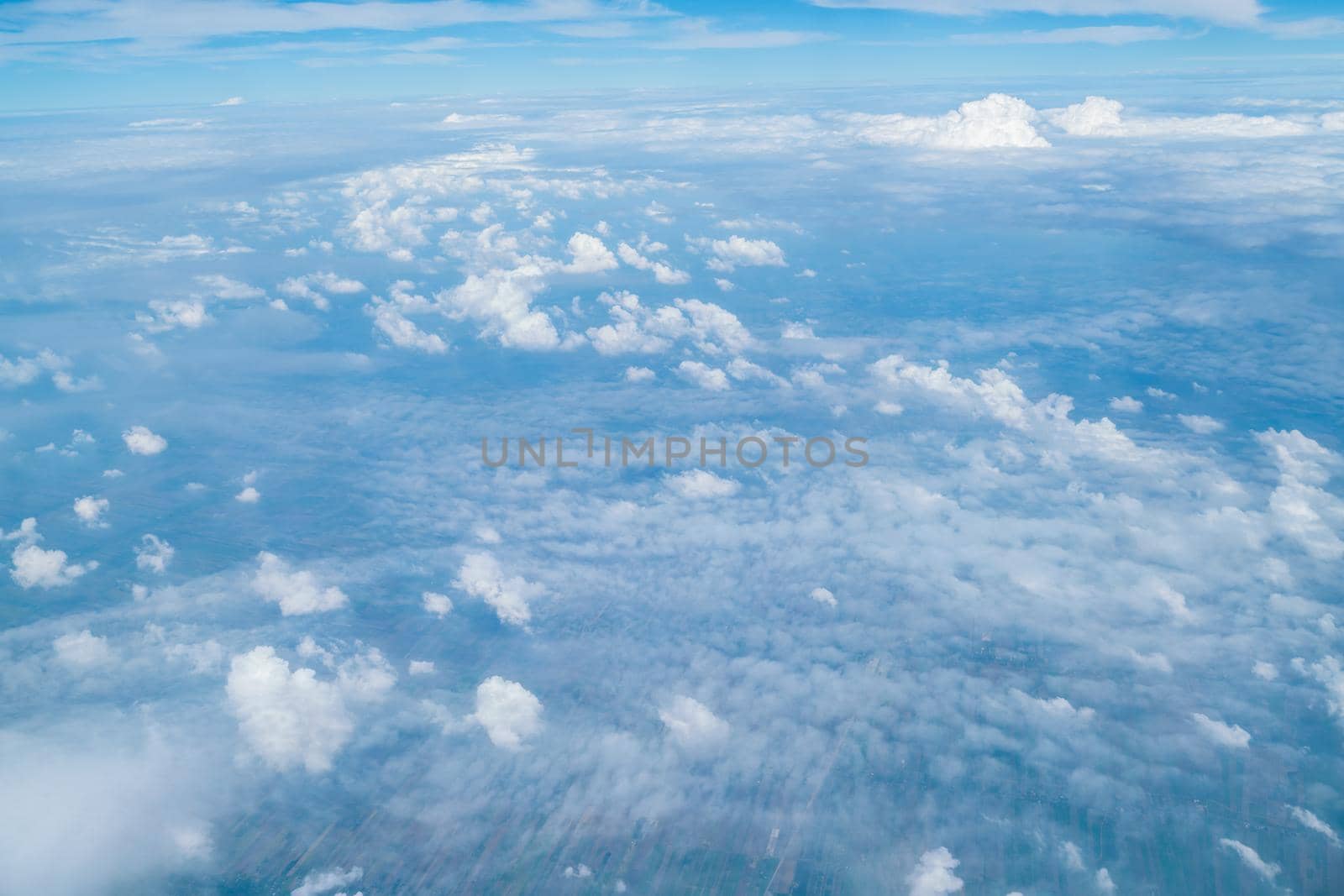 White clouds and blue sky view from airplane window. Beautiful cloudscape from sky aerial view. Beauty of nature view from above the sky and clouds. Sunlight in the sky shines on clouds.