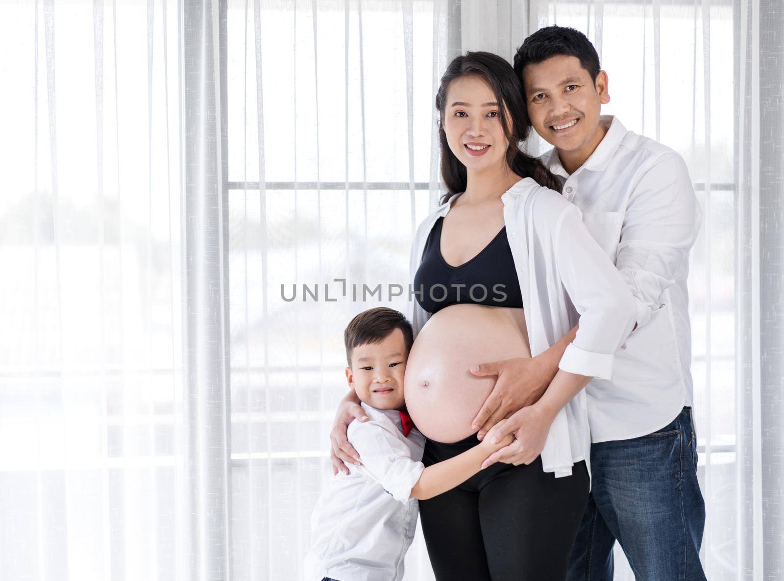 happy family, pregnant mother, father and son hugging by geargodz