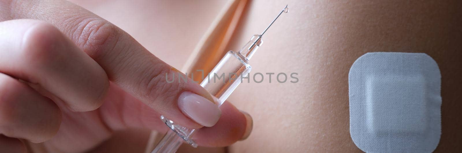 A woman holds a syringe with a medication, close-up. Beauty injections, plaster on the arm. Virus vaccine