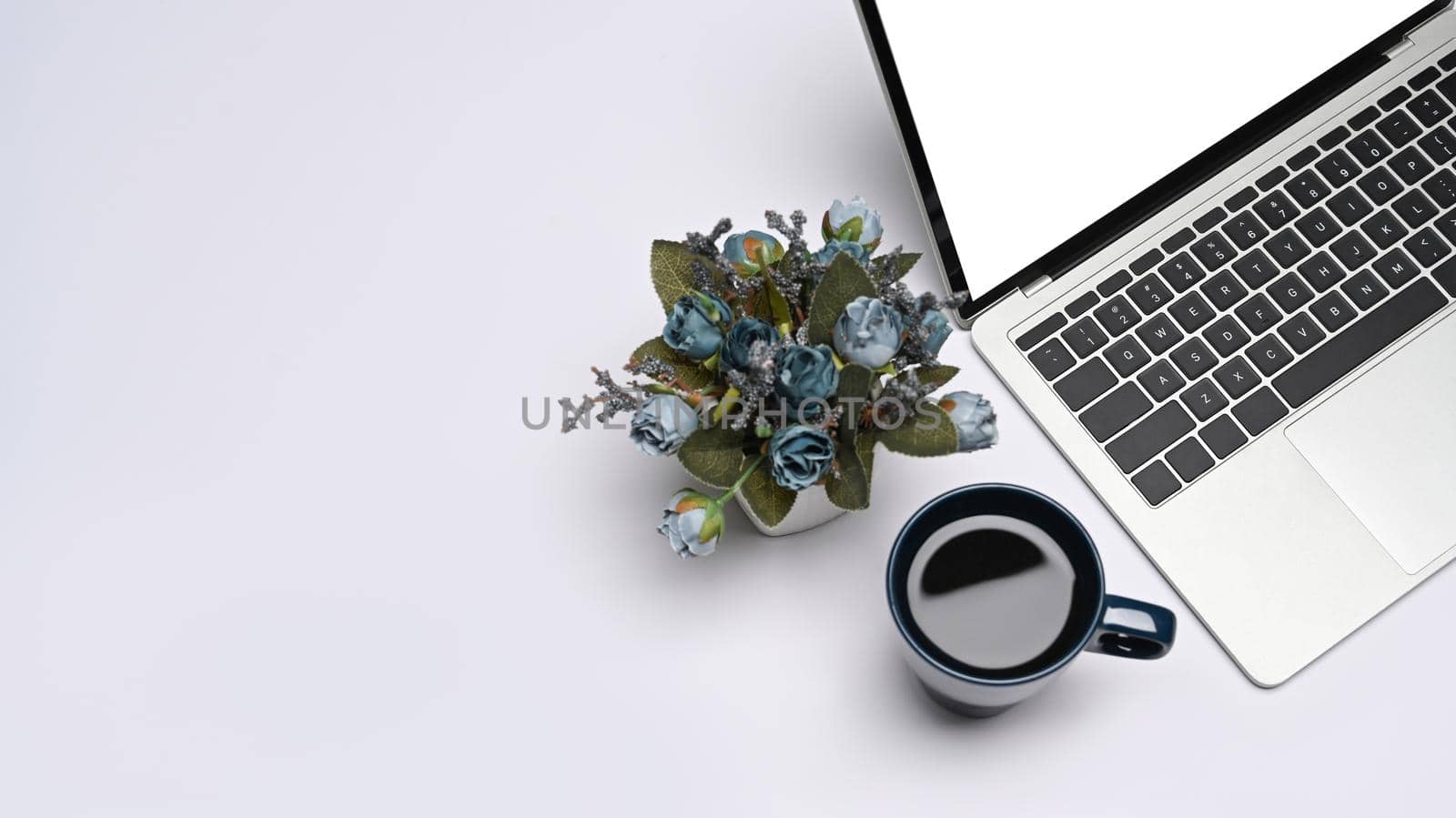 Mockup laptop computer with empty display, coffee cup and flower pot on white background. by prathanchorruangsak
