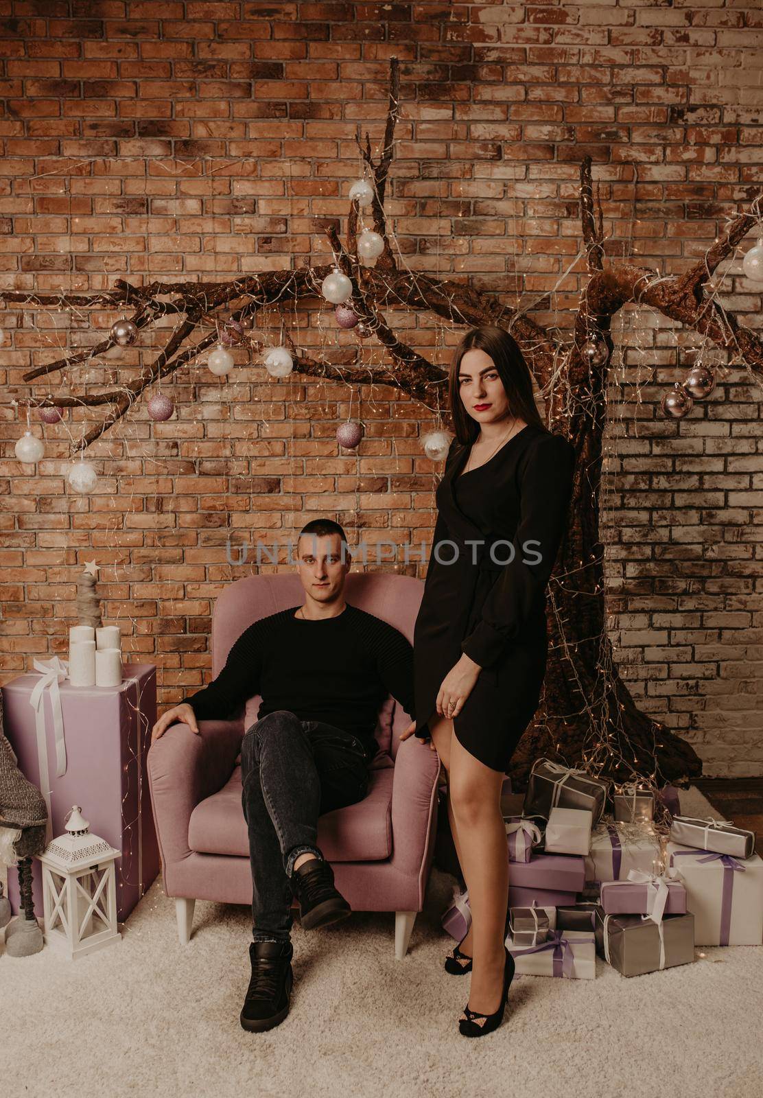 In love young couple man and woman hugging kissing near a Christmas tree in elegant clothes. decorated house for New Year. Christmas morning. apartment interior. Valentine's Day celebration