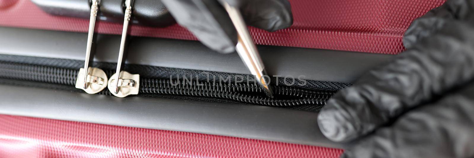 Gloved hands mending a snake on a suitcase, close-up. Shoemaker tailor tool for repairing snake on bags and clothes, tailor shop