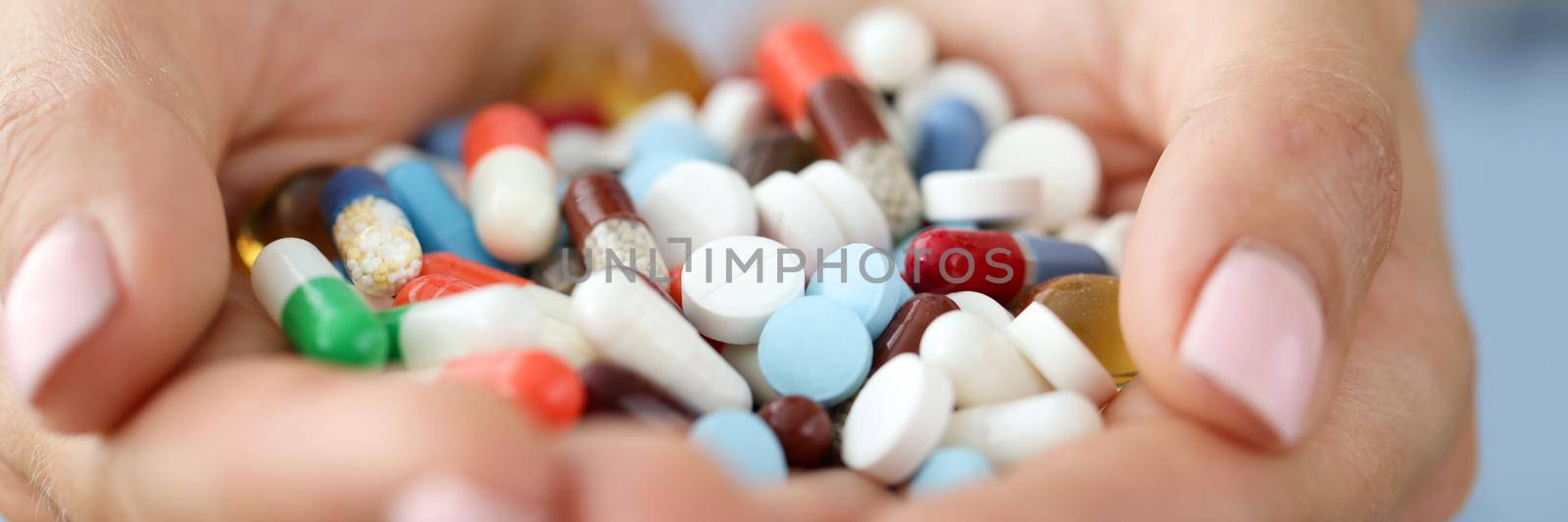 Colored pills and capsules in the palms, close-up. Food supplements, homeopathy. Treatment during a pandemic