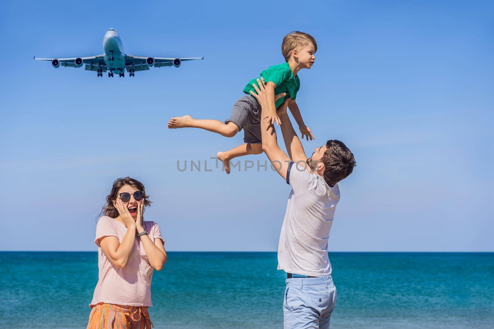 Happy family have fun on the beach watching the landing planes. Traveling on an airplane with kids concept. Text space. Island Phuket in Thailand. Impressive paradise. Hot beach Mai Khao. Amazing landscape.