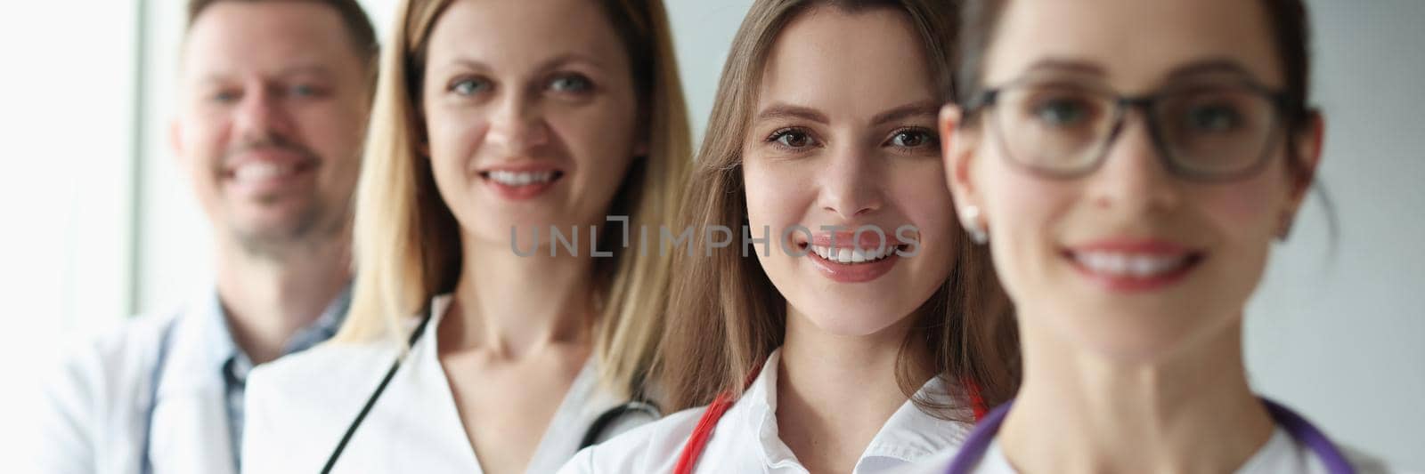 Group of joyful practicing young doctors in uniform, close-up. Hospital first aid, medical professional