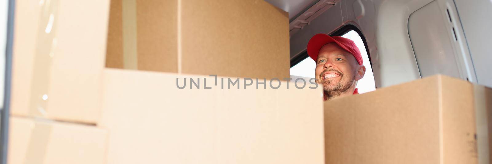 A man postman is looking for a parcel in the truck, boxes close-up. Express delivery of goods to your home during quarantine