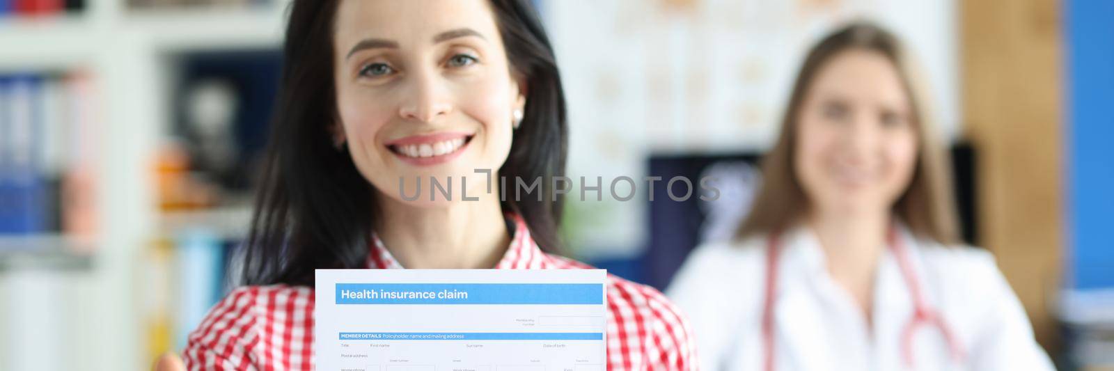 Happy woman shows document about health insurance, close-up. Insured event, doctor's consultation. Health expenses