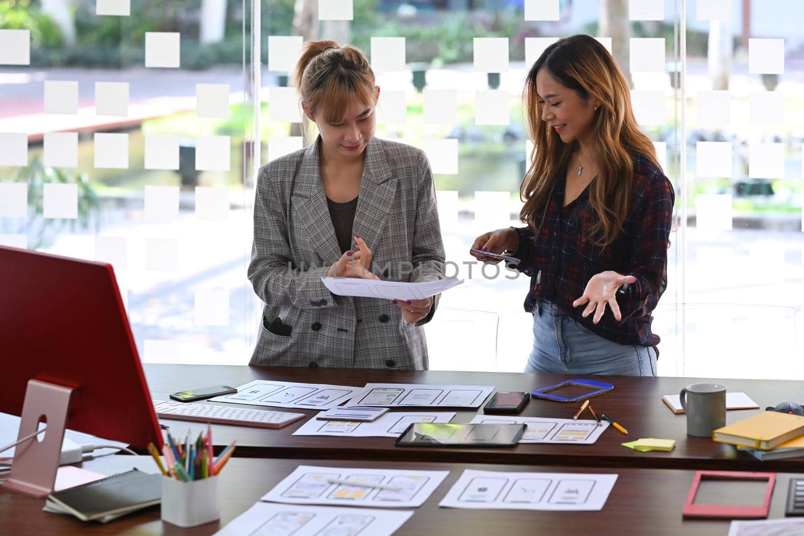 Two creative women are planning application and developing template layout, framework for mobile phone.