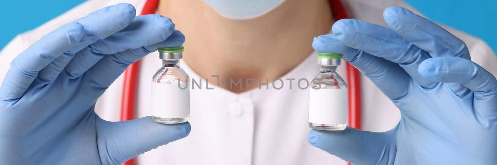 A nurse holds ampoules with medicine in her hands, close-up. Virus vaccine, immunization. Medication for infection, dose in a vial